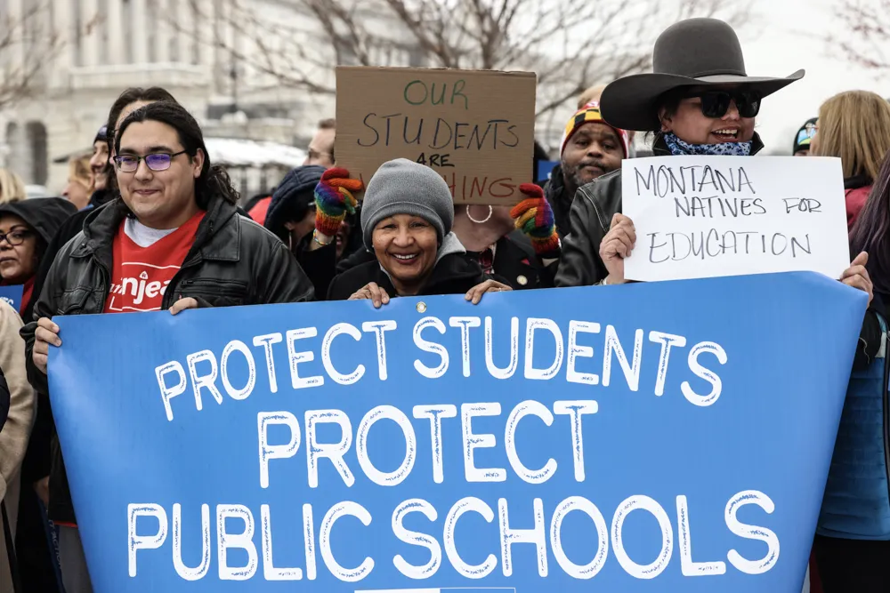 Three educators stand in front of a banner saying "protect students, protect public schools."