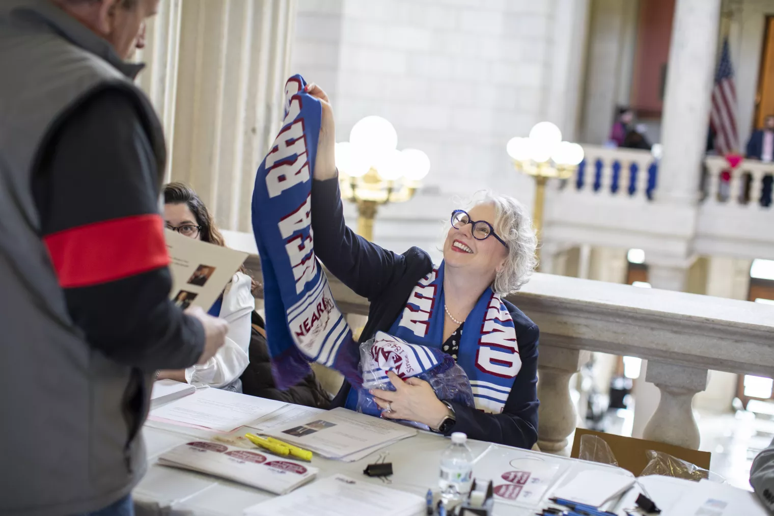 A NEARI staff member handing out a NEARI scarf at Lobby Day 2024 check-in