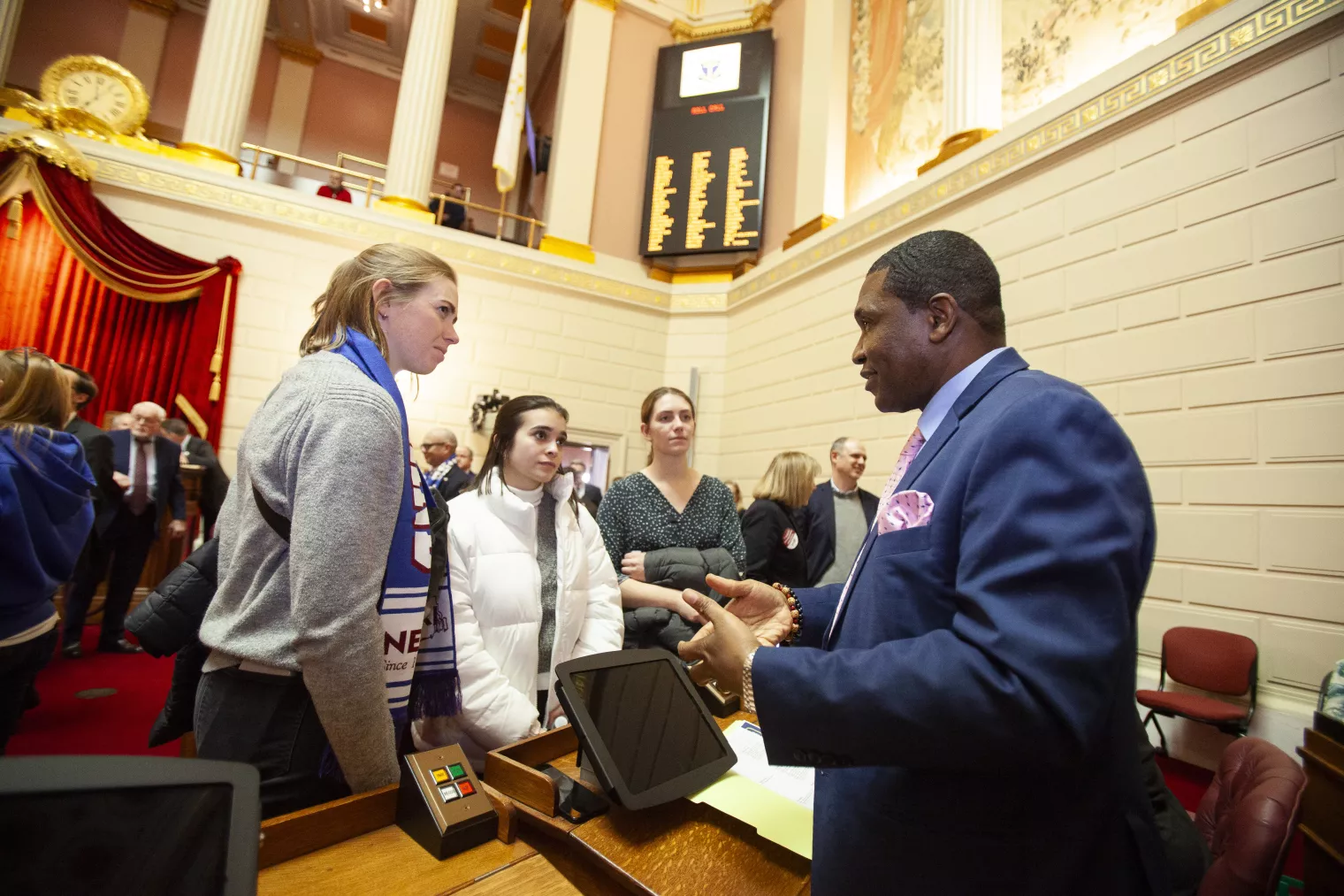 NEARI members on Capitol Floor talking together in the well at Lobby Day 2024