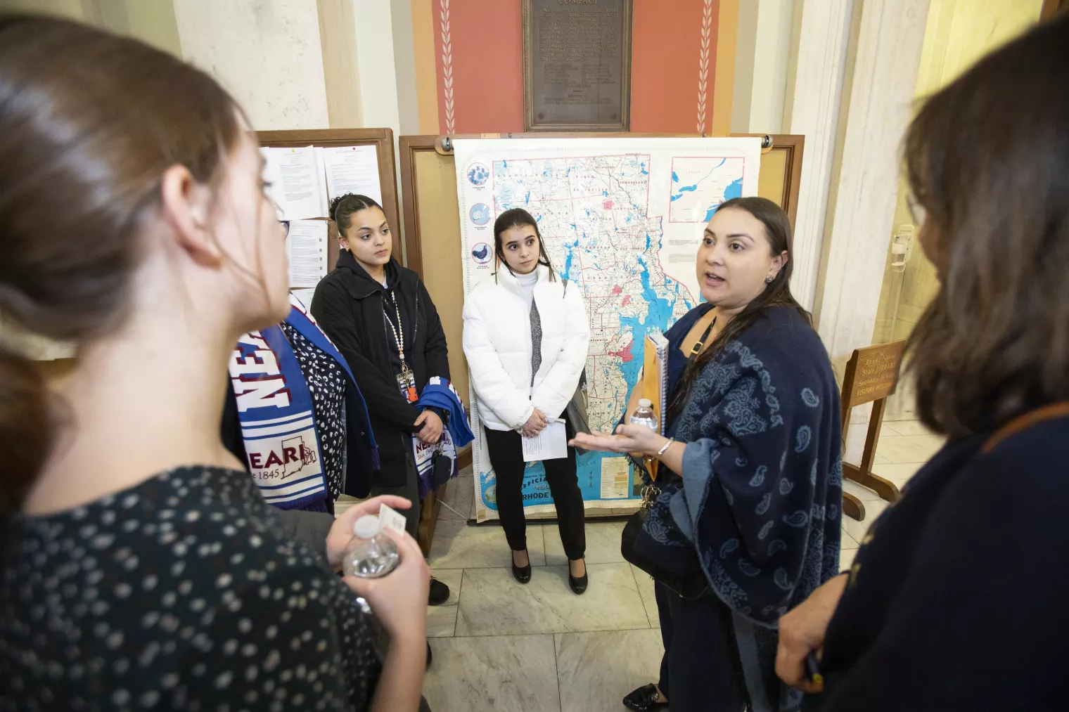 NEARI members talking together in front of maps at the State House on Lobby Day 2024.