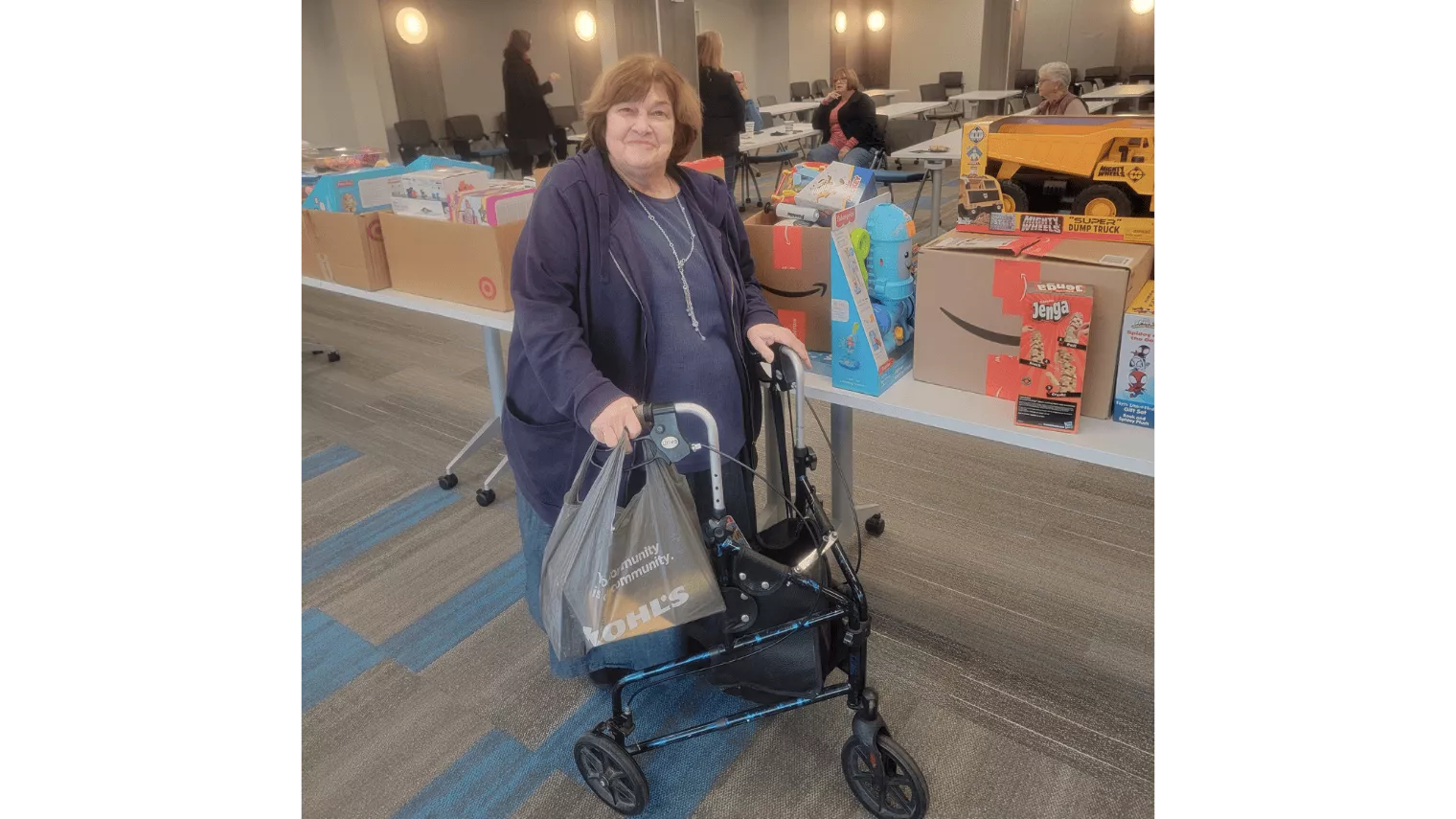 Fran Harris standing amongst many holiday gifts during the Toy Drive