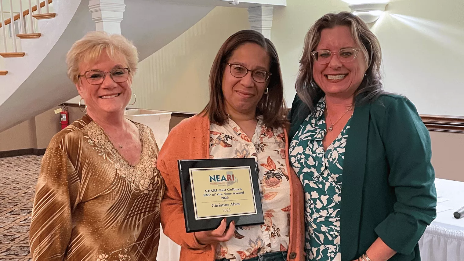 Three woman smiling holding the ESP of the Year Gail Colburn Award