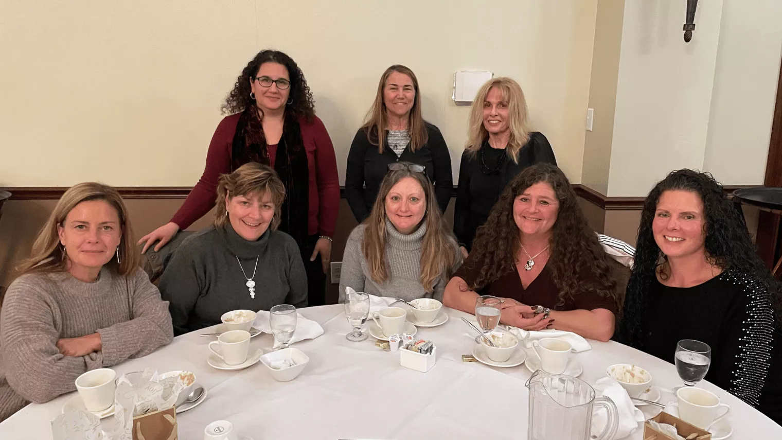 A group of women smiling and seated at a dinner table