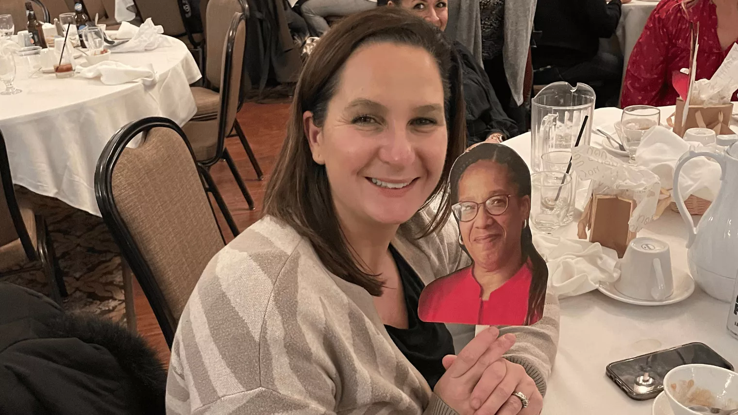 Smiling woman with Christine Alves cutout on a stick