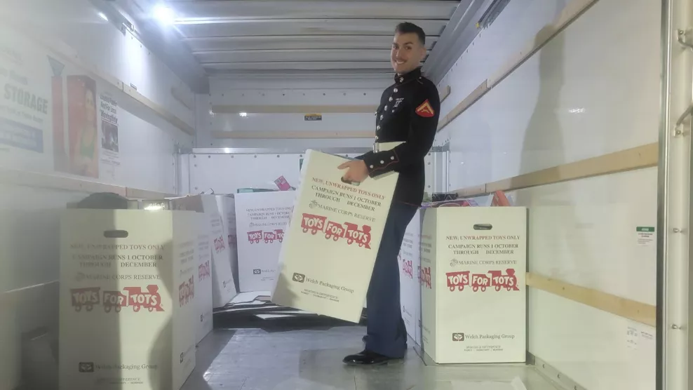 Marine reservist packing a trailer truck with bins full of toys