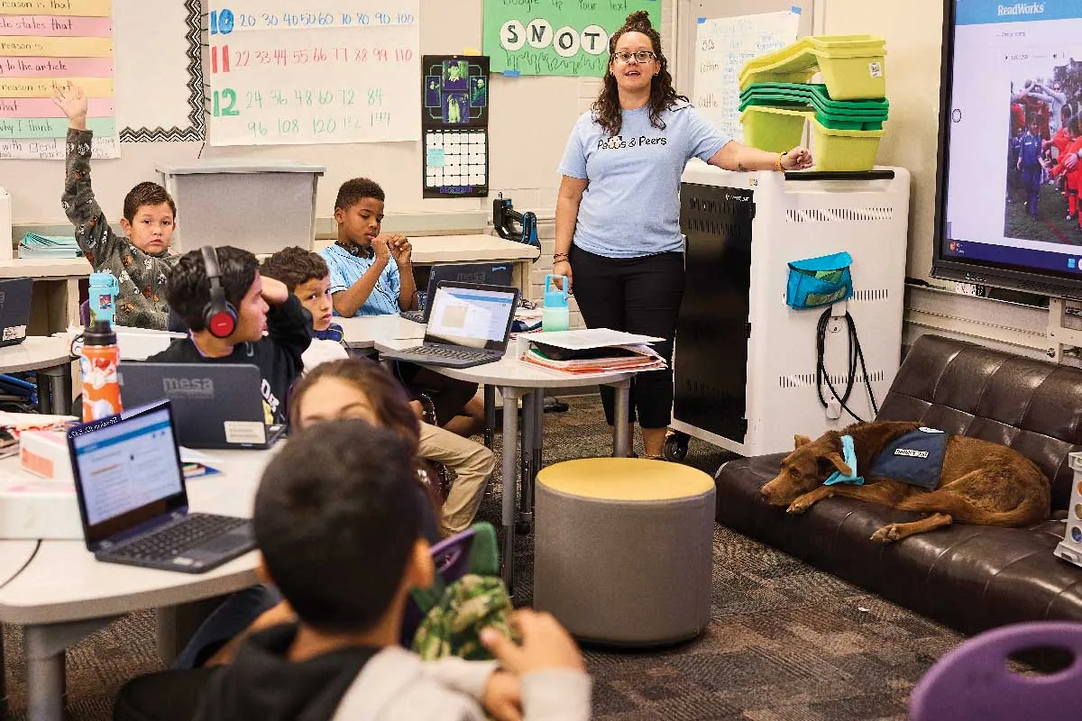 Arizona teacher Lindsay Dominguez with her canine “co-teacher,” Hotch, napping on the couch in a classroom with students.