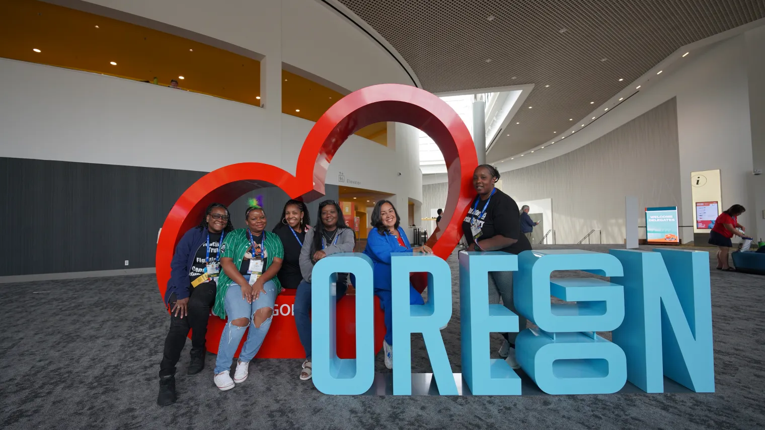 Several NEA members pose with the Heart Oregon sign in the Oregon Convention Center in Portland