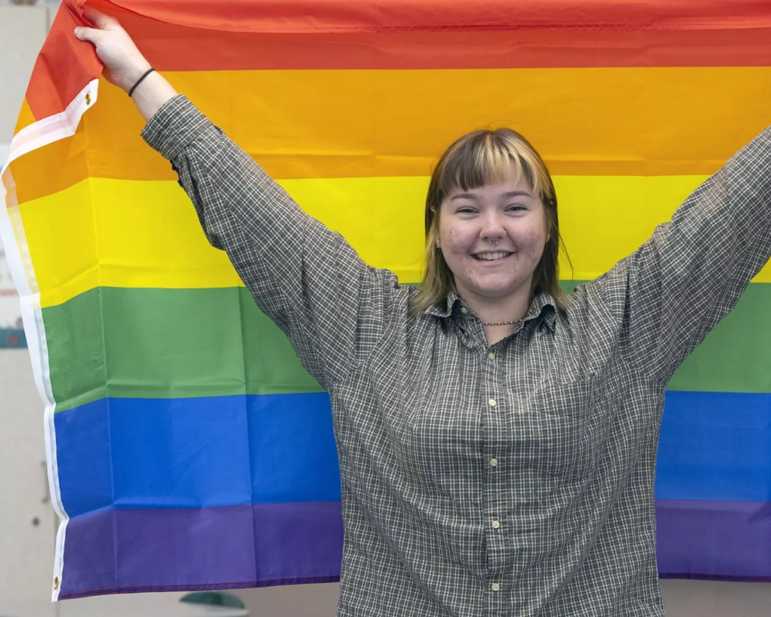 Student holds up rainbow flag in school hallway