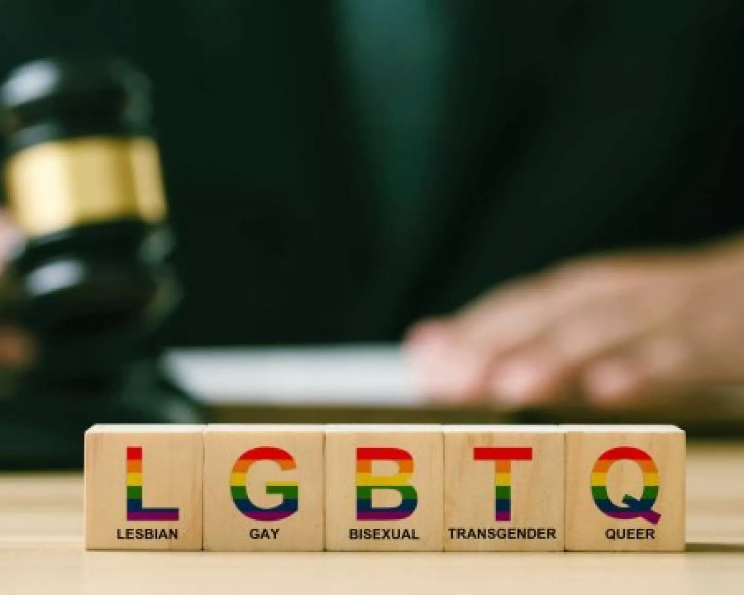 A row of toy blocks spells out LGBTQ while a judge bangs a gavel in background
