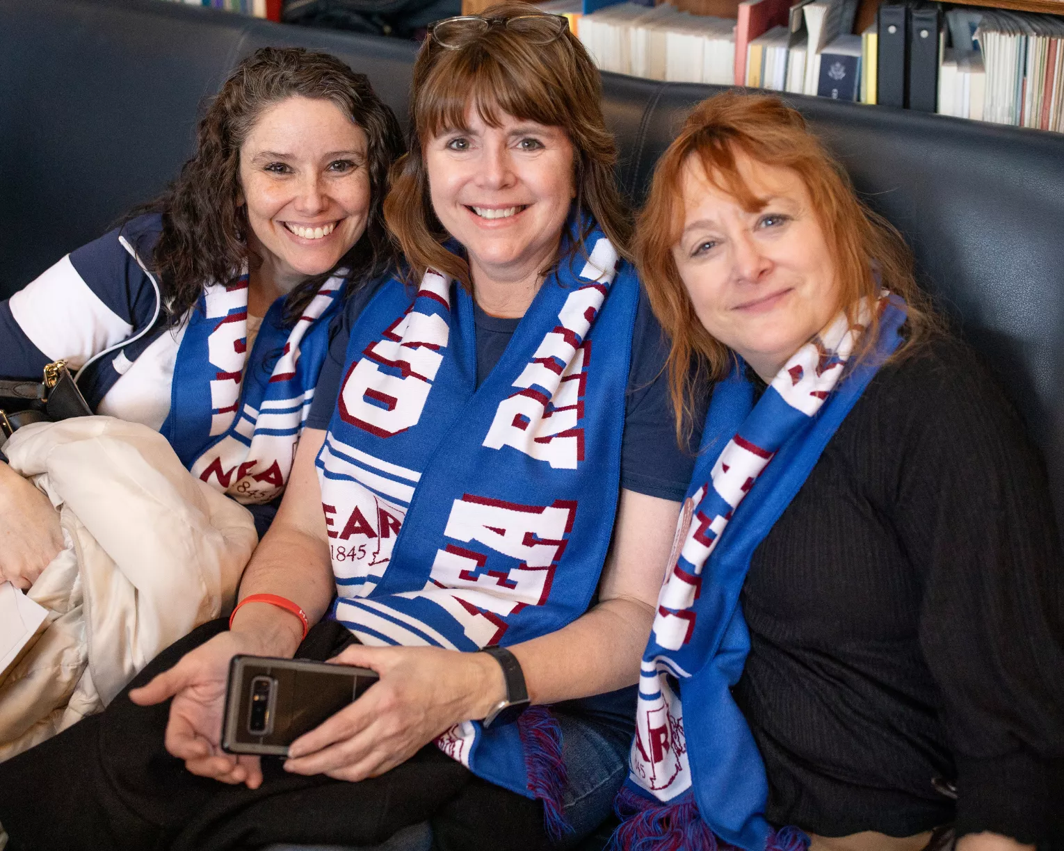 NEARI members smiling together on a couch at the State House wearing NEARI scarves.