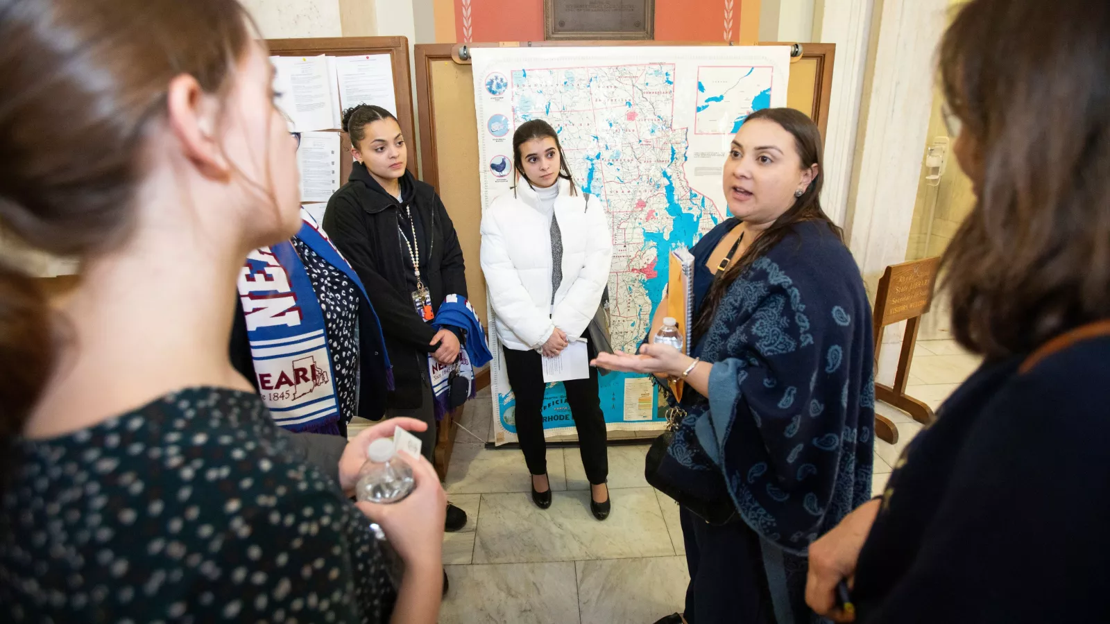 NEARI members talking together in front of maps at the State House on Lobby Day 2024.