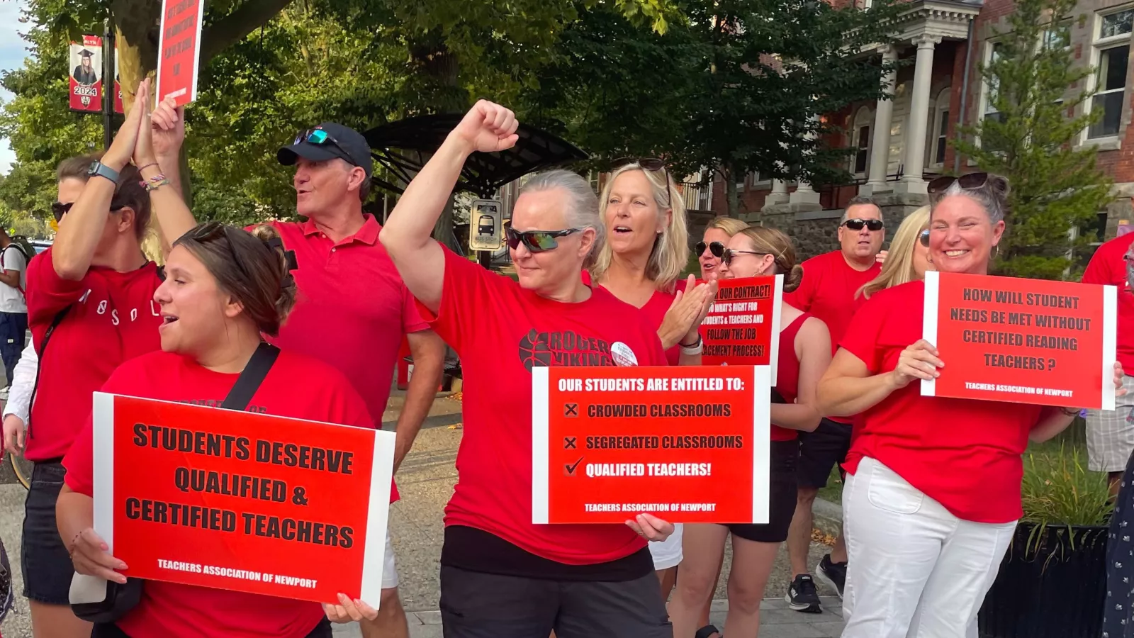 Teachers Association of Newport (TAN) members flex and smiling on a picket line-