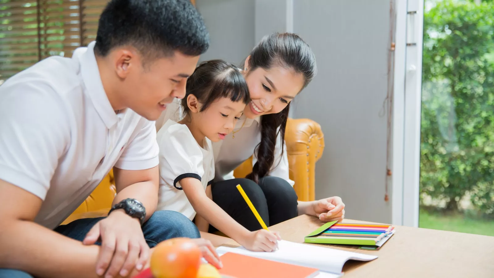 A family sits with a small child working on homework.