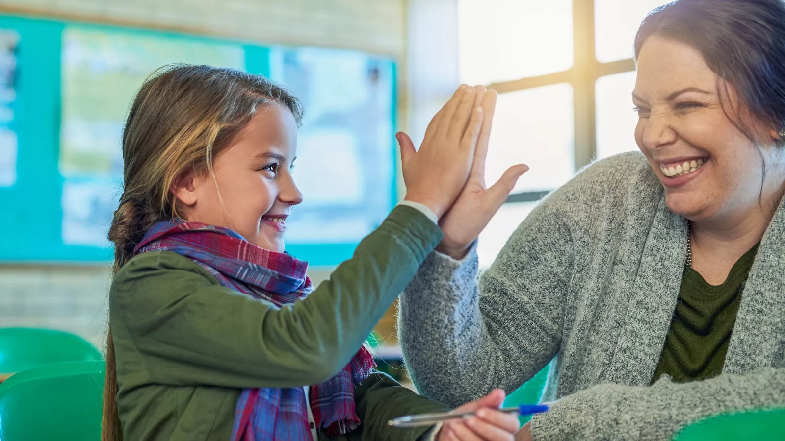 An elementary school student high-fives a teacher