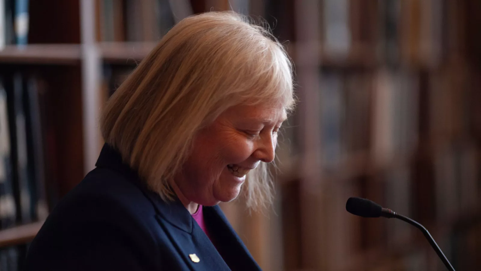 Valarie Lawson smiling at her notes at the podium while speaking at the NEARI Lobby Day press conference in 2024