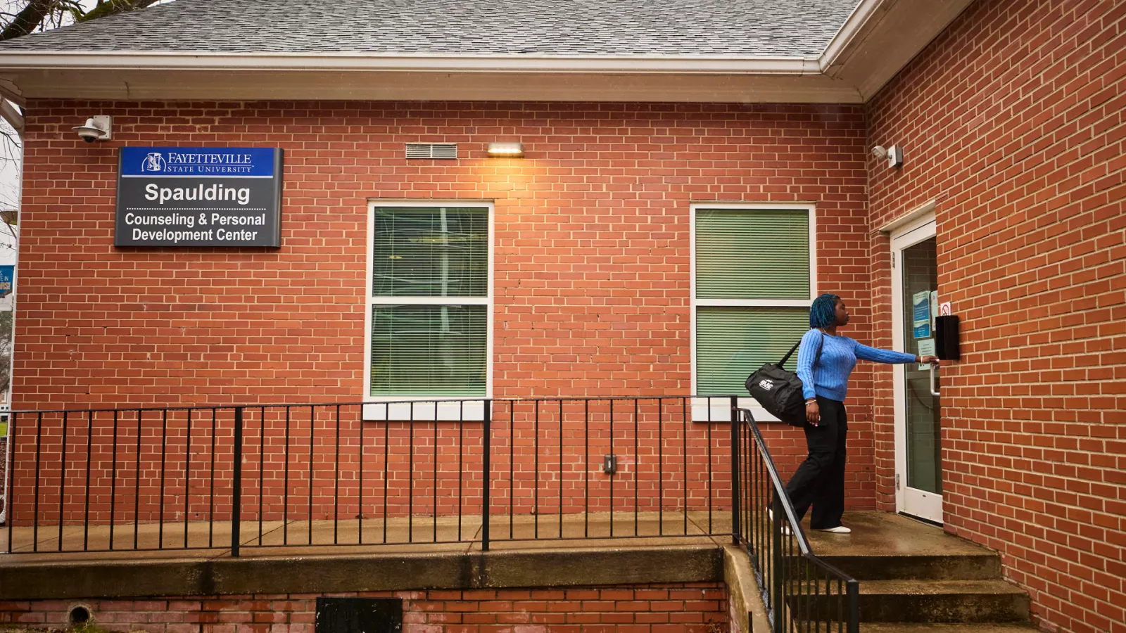 A woman in a blue center entering a red-brick building