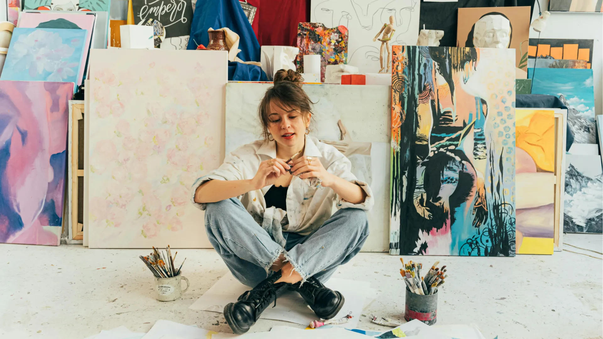 young artist sitting in front of art canvases