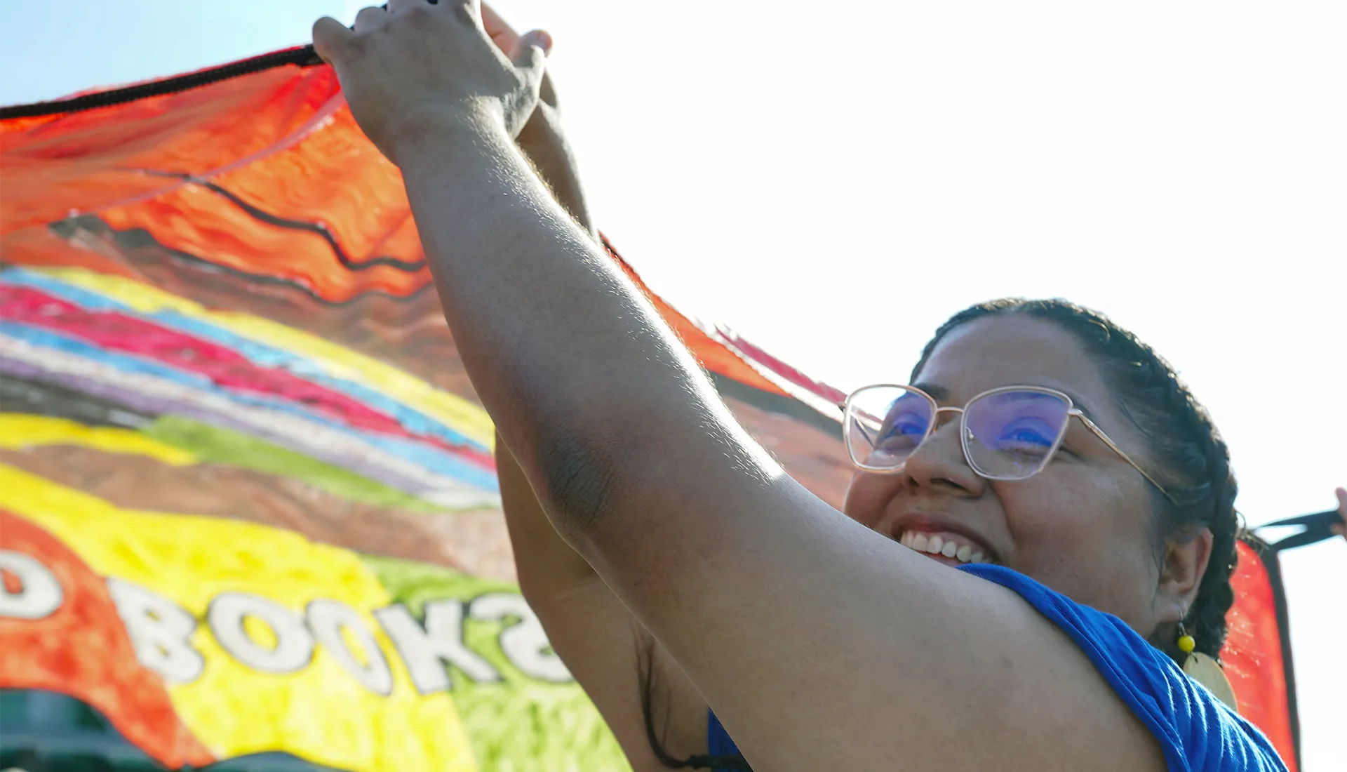black woman in glasses holds up part of a large canvas artwork