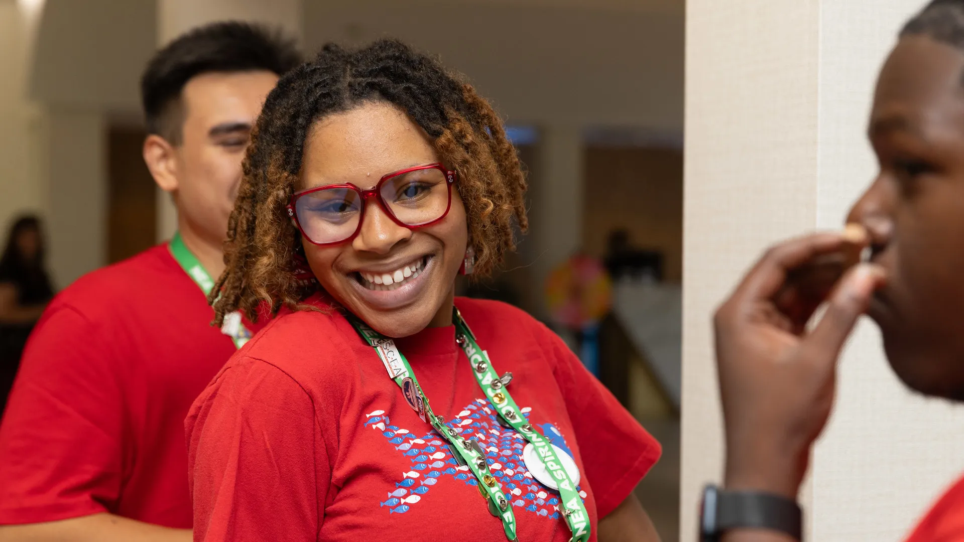 A woman with a big smile and red glasses looks directly into camera.