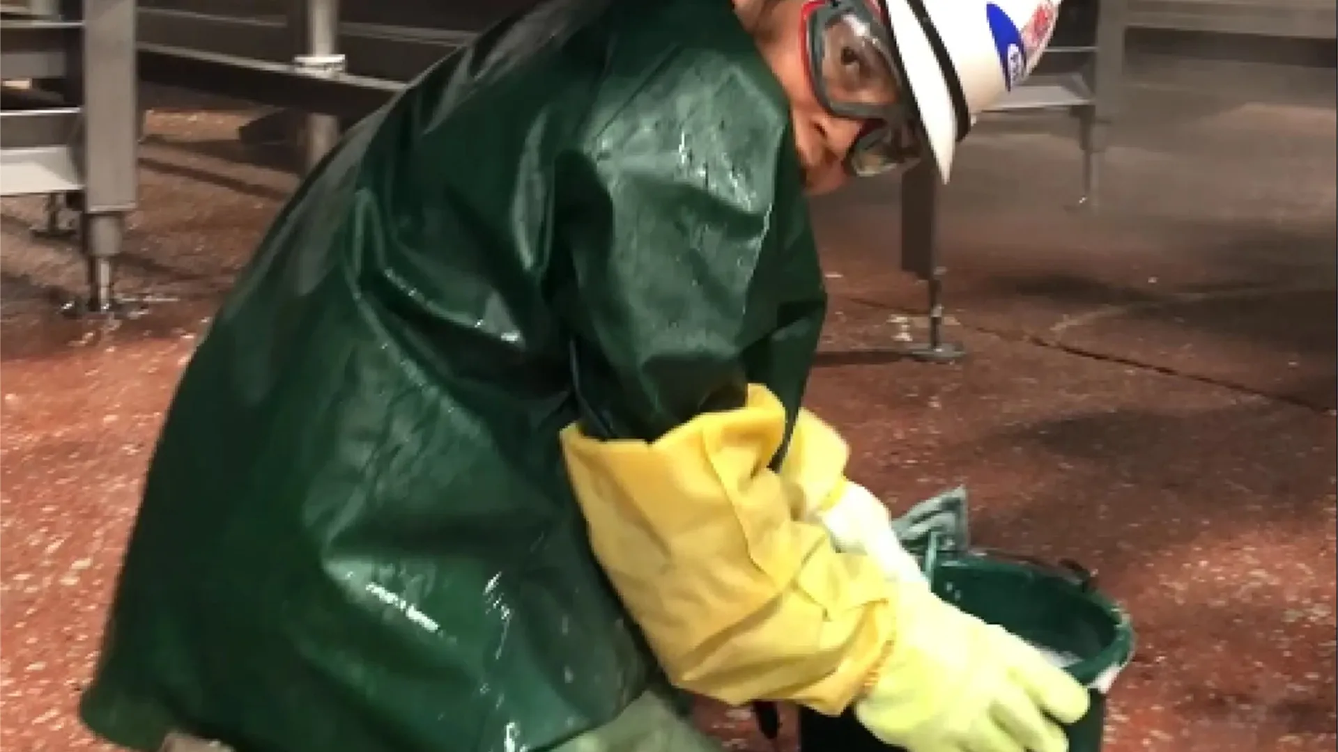 A child in a green and yellow suit cleaning a surface with a cloth.
