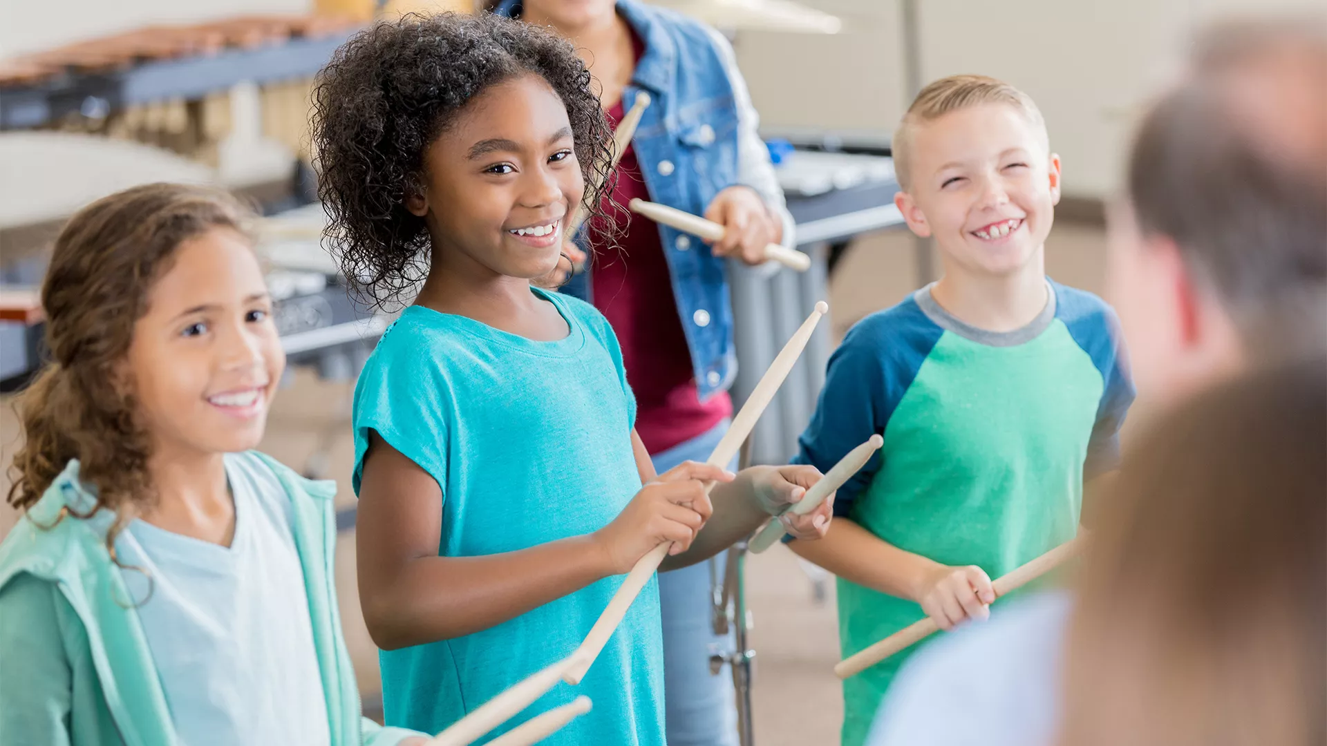 elementary students in class using drumsticks in a rhythm activity