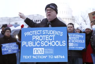 A man addresses a rally crowd with the U.S. Capitol as a backdrop.