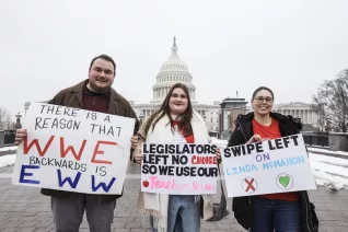Three people stand near the U.S. Capitol Building holdings signs that disapprove of Linda McMahon as the nominee to the U.S. Department of Education