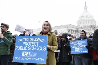 A woman in a green coat speaks to a crowd in front of the U.S. Capitol Building