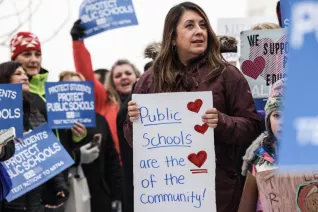 A crowd of people holding various signs about supporting public education.