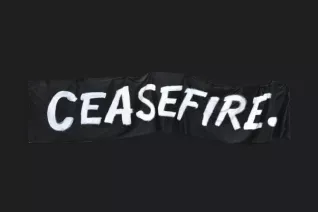 A black black ribbon has the word "CEASEFIRE." in white in an all-caps sans serif font against a black background.