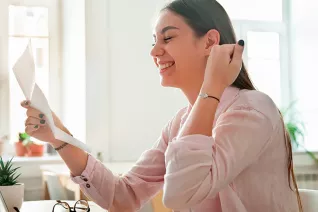 A woman hold a paper and grinning