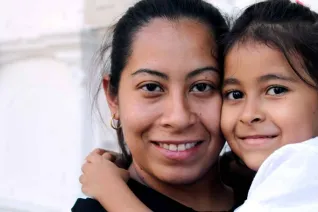 An immigrant mother and daughter smiling