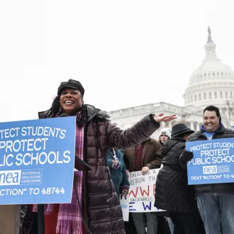 An African American woman speaks at a rally with the U.S. Capitol as her back drop.