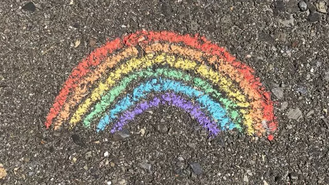 A chalk drawing of a rainbow on a sidewalk