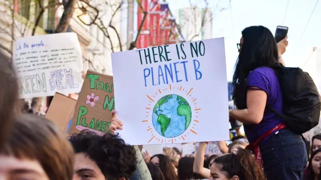 Climate change activists at a march. One is holding a sign that says "There is no Planet B." with a picture of planet Earth on the sign.
