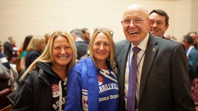 NEARI Members smile with a legislator on the floor at the Capitol on Lobby Day 2024.