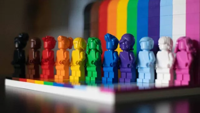 Rainbow colored Lego people lined up in the order of the Inclusive PRIDE Flag.