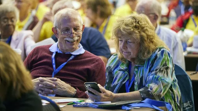 Retirees at a conference looking at their phone