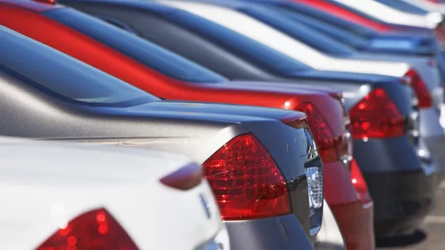 A picture showing the back bumpers of several cars in a car sales lot